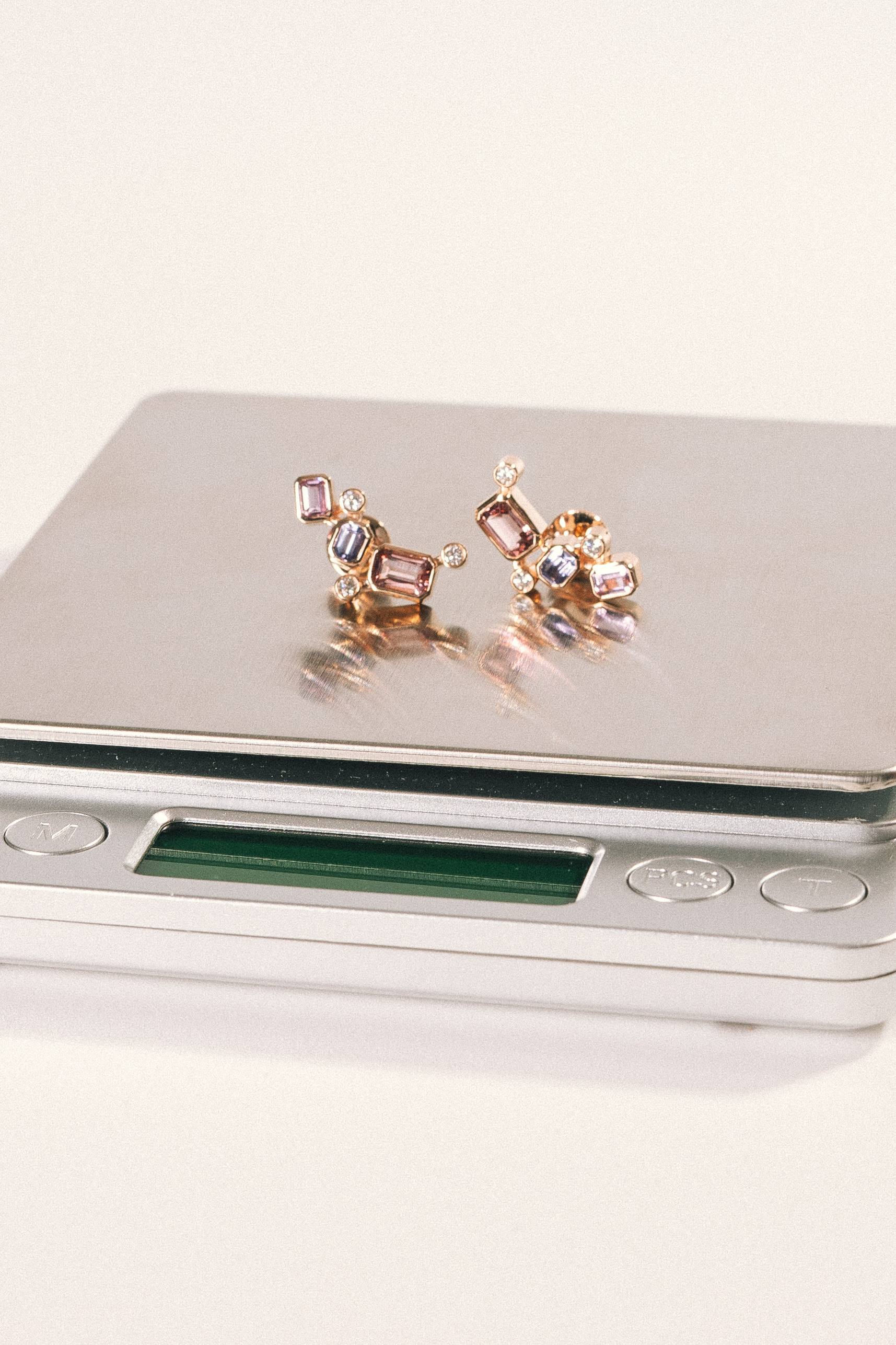 Bespoke gem-set stud earrings on a jeweller's scale